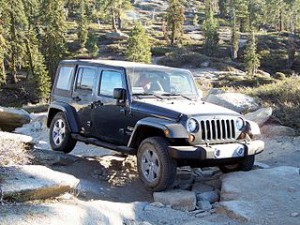 Black 2008 Jeep Wrangler driving over large rocks